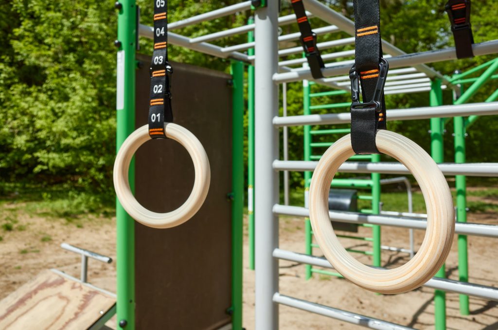 Wooden gymnastic rings hanging in a open air gym.